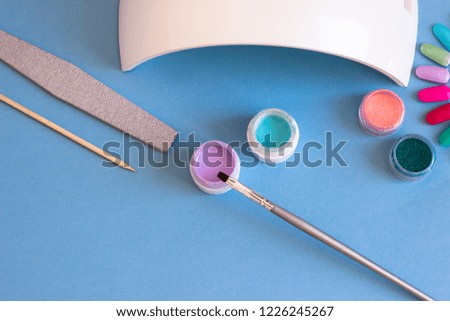 Set of cosmetic tools for manicure and pedicure on a blue background.
Bottles of nail polish, glossy design for nails. Manicure - creation tools, UV lamps, beauty, care concept.