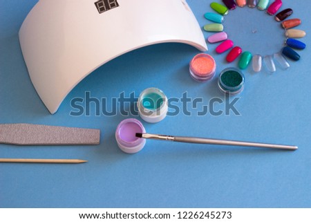 Set of cosmetic tools for manicure and pedicure on a blue background.
Bottles of nail polish, glossy design for nails. Manicure - creation tools, UV lamps, beauty, care concept.