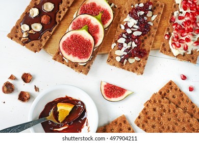 Set Of Crisp Rye Bread Sandwiches With Fig, Cranberry Jam And Almond, Soft Cheese, Chocolate Paste And Hazelnut Over White Background. Top View.