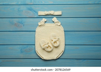 Set Of Cute Baby Knitwear For Photoshoot On Light Blue Wooden Background, Flat Lay