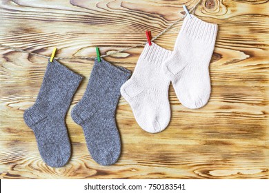 Set Of Cute Knitted Cashmere Newborn Baby Socks  Hanged On Pins Against Wooden Background.