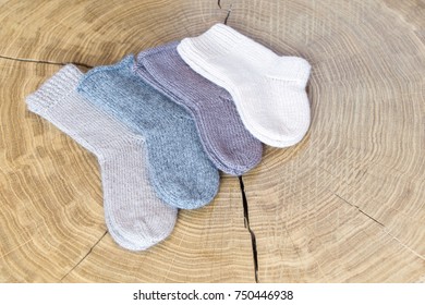 Set Of Cute Small Different Colored Cashmere Knitted Newborn Baby Socks On A Wooden Desk Background.