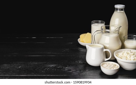 Set of dairy products on black wooden background, assortment of milk, cottage cheese, sour cream and yogurt with copy space
