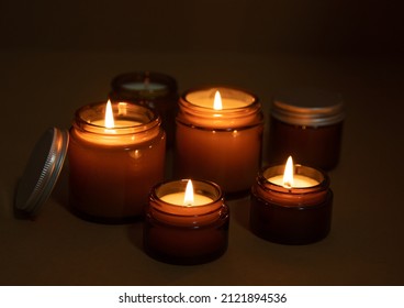 A set of different aroma candles in brown glass jars. Scented handmade candle. Soy candles are burning in a jar at night. Aromatherapy and relax in spa and home.