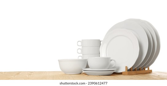 Set of different clean dishware on wooden table against white background