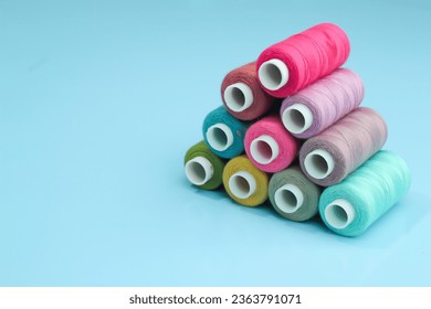 Set of different colorful sewing threads on light blue background, flat lay. With space for text.