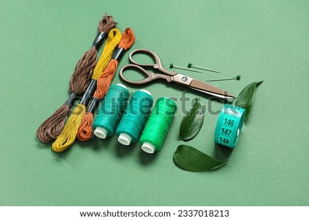 Set of different embroidery supplies on dark green background