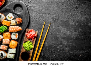 Set of different kinds of sushi rolls with salmon, shrimp and vegetables. On black rustic background