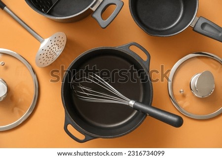 Set of different kitchen utensils on orange background