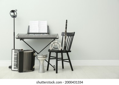 Set of different musical instruments and microphone near white wall indoors, space for text
