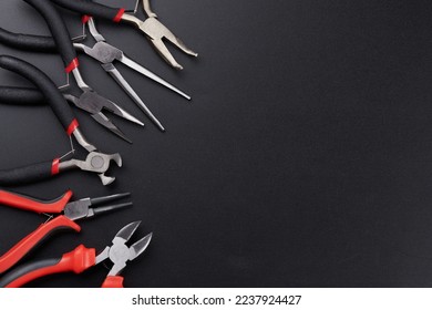 Set of different types of pliers and side cutters isolated on black background. Hand tools for repair, construction and maintenance