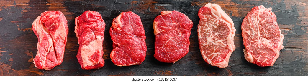 A set of different types of raw beef steaks:top blade, rump, chuck eye roll over old wooden background top view banner size. - Shutterstock ID 1831542037
