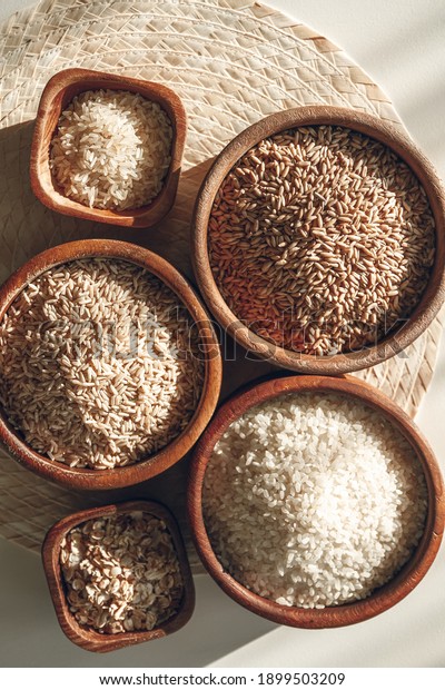 Set of different types of rice and cereals in the\
wooden bowls