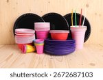 Set of disposable plastic tableware on light wooden table