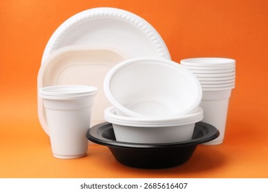 Set of disposable plastic tableware on orange background, closeup