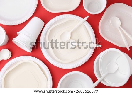 Set of disposable plastic tableware on red background, flat lay