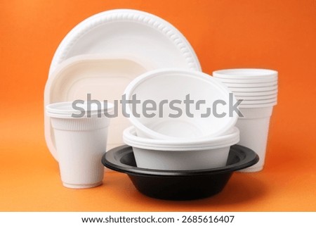 Set of disposable plastic tableware on orange background, closeup