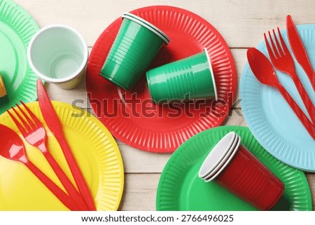 Set of disposable plastic tableware on wooden table, flat lay