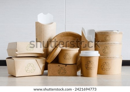 A set of disposable tableware made of cardboard and paper with recycling signs. Packaging for food delivery or for a picnic made from environmentally friendly materials.