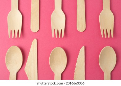 Set of disposable wooden knives, spoons and forks on a pink background. Plastic free concept, zero waste, environmental protection. Simple minimal creative layout in fashionable color.