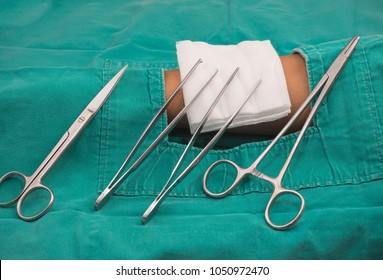 Set of dressing.Medical nursing set contains of tooth forceps,scissor tweezers, gauze pieces with white tray, Handle clip, cotton and wound dressing,Set of dressing on green napery.