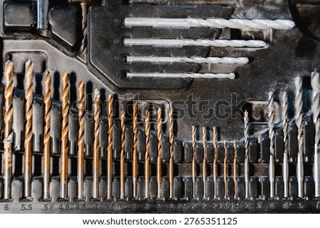 Set of drill bits and tools arranged in case showing different sizes and types for construction work, equipment collection