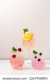 Set of drinks with ice in glasses. Raspberry, blueberry and orange cocktails. Refreshing tropical summer fruit lemonades