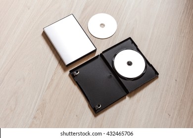 Set Dvd Or Cd Disc Cover Case Mockup With Open Plastic Box. Template Disc With White Isolated Free Space For Design. Mock Up With Black Package For Compact Or Dvd Disc. On Wooden Table Background