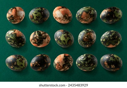 Set of Easter eggs colored with natural, various plants dyes. Creative Easter pattern layout from traditionally colorful eggs on dark green background, top view.