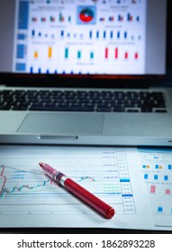 Set Of Economic Scenario, Accounting Desk. Computer With Economic Blurred Reports And Red Pen For Work