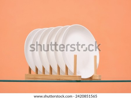 Set of empty white plates on a wooden utensil stand. Ceramic crockery.
