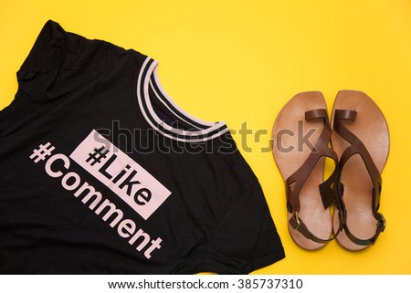 Set of  essential objects of a stylish blogger girl. Black top with web social hashtags and leather sandals on yellow background.