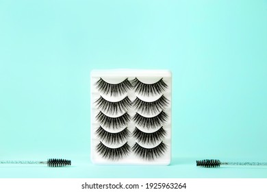 SET OF FALSE EYELASHES EXTENCIONS ON BLUE TURQUOISE BACKGROUND WITH LASH BRUSHES 