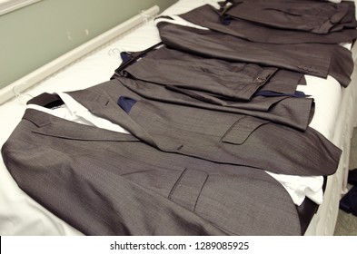 A Set Of Fashionable Best Mens Grey Wedding Suits, Suit Tops And Trousers, Laid Out Ready For The Groomsmen To Get Changed Into. Getting Ready At A Wedding Celebration.