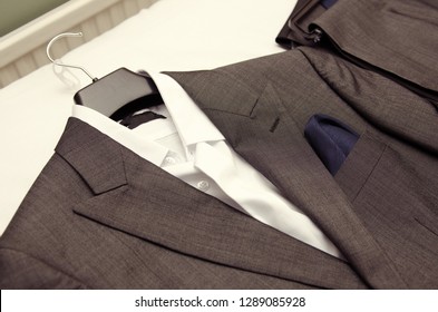 A Set Of Fashionable Best Mens Grey Wedding Suits, Suit Tops And Trousers, Laid Out Ready For The Groomsmen To Get Changed Into. Getting Ready At A Wedding Celebration.