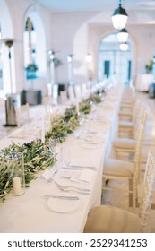 Set festive long table with invitations near plates in a large hall