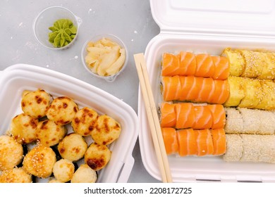 Set Of Fish Sushi Rolls With Salmon And Sesame, Ginger, Wasabi Packed In Plastic Disposable Food Container Box On Gray Background. Seafood, Food Delivery,take Out Service From Restaurant Concept.