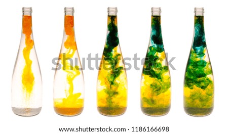 Set of five figured bottles with dymanic effect of water smoke using yellow and blue food coloring isolated on a white background.