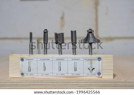 Set of five quarter inch hardened steel woodworkers router bits with description and sizes set in a piece of wooden board