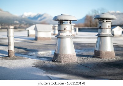 Set of flat roof vents on building with modified bitumen roofing system. Group of different shaped metal ventilators such as: bathrooms and laundry exhaust and plumbing stack vent. Selective focus.