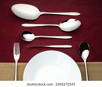 a set of flatware on red background with sppon and fork on a plate