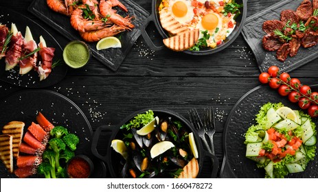 Set of food from meat, fish and salads on black background. Top view. Assortment of healthy food.