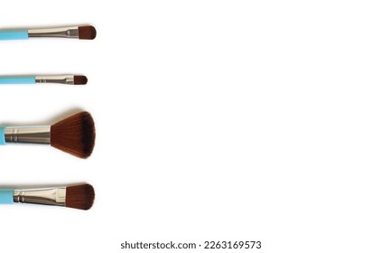 A set of four makeup brushes of different shapes on a white background. Four blue makeup brushes in different shapes and sizes. Fashion accessories for cosmetics. Free space for text