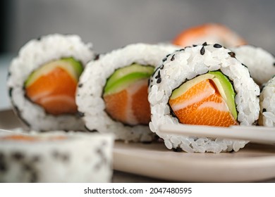 A set of fresh sushi rolls with salmon, avocado and black sesame seeds close up. California roll, selective focus