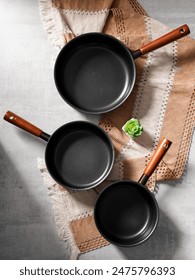 Set of frying or cooking pans. They are nonstick and iron cast. A set of pans from different size. Nonstick cookware is good for home usage only. The coating can be easily removed depend on quality