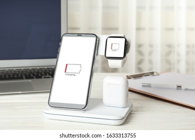 Set of gadgets charging with wireless device on white wooden table