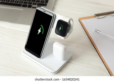 Set of gadgets charging with wireless device on white wooden table