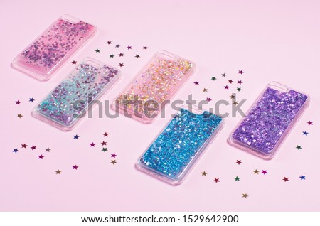 Set of glitter phone cases isolated on pink background back view. Glitter liquid phone case. Phone case mockup