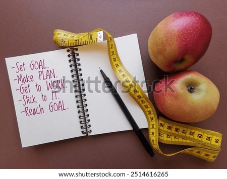Set goal make plan get to work stick to it reach goal. Fitness motivation quote written on notepad. Positive inspirational message on notebook with apples and measuring tape. Motivational workout note