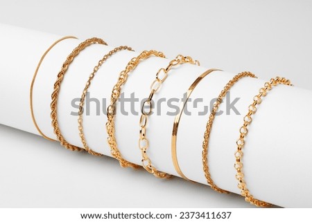 Set of golden bracelets on display on white background